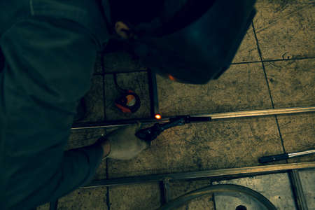 The welder lights the arc and begins to weld the metal structure of stainless steel