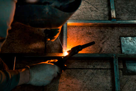 The welder lights the arc and begins to weld the metal structure of stainless steelの写真素材