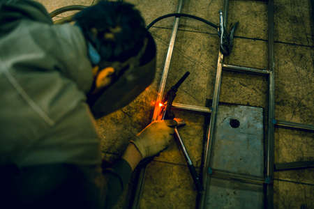 The welder lights the arc and begins to weld the metal structure of stainless steel