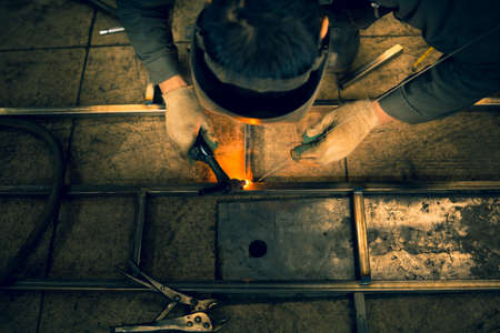 The welder lights the arc and begins to weld the metal structure of stainless steel