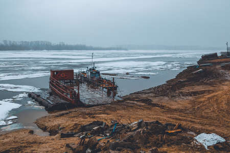 The boat with the barge is moored to the river bank and is waiting for the opening of the navi-gationの写真素材