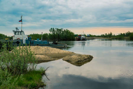 A boat with a barge carries traffic across the river on a ferry crossingの写真素材