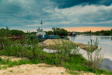 A boat with a barge carries traffic across the river on a ferry crossing