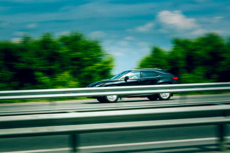 The car at high speed rushes along the motorway in the early July morningの写真素材