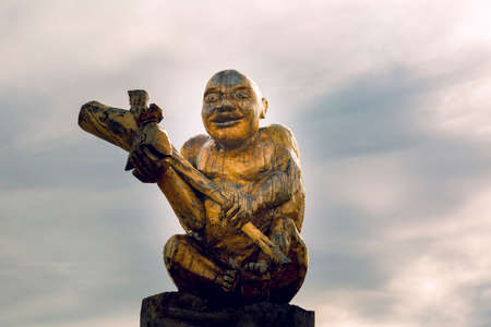 Cut from a log statue of a peasant close-up with a club in his hands