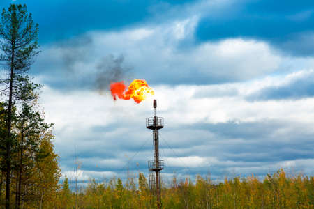 The flame of a gas torch develops in the wind against the backdrop of a dramatic skyの写真素材