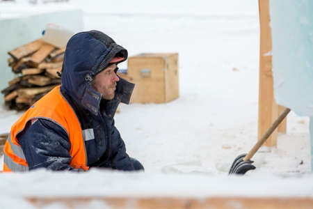 Worker fitter in a protective helmet and reflective vest on the working meast
