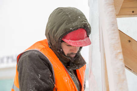 Worker fitter in a protective helmet and reflective vest on the working meast