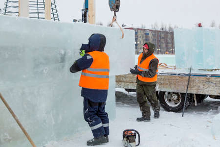 Workers build an ice town from ice blocks for the Christmas holidays