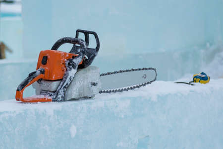 On the ice plate lies a chainsaw and tape measureの写真素材