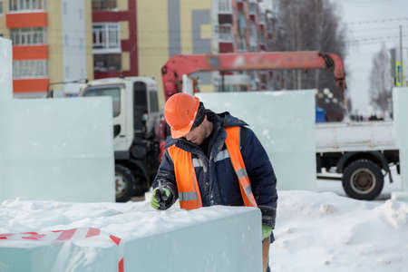 Portrait of a fitter slinger in an orange vest and helmet on unloading ice platesの写真素材