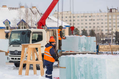 Assemblers unload ice panels from a car using a craneの写真素材