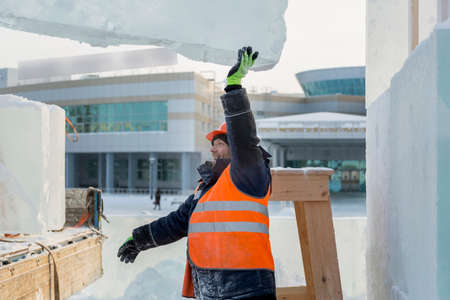 Sling fitter in a jacket and helmet unloads ice blocksの写真素材