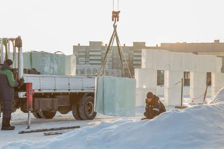 Sling fitter in a jacket and black hat unloads ice blocksの写真素材
