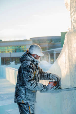 The sculptor cuts ice contours from ice with a chainsaw for Christmasの写真素材
