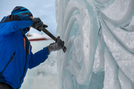 The sculptor cuts an ice figure for Christmas from a block of ice with a chisel