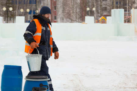 Worker with a bucket in hand at the assembly site of the ice townの写真素材