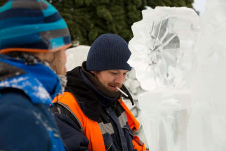 A worker with a cigarette in his mouth at the ice figure talks to a friend.の写真素材