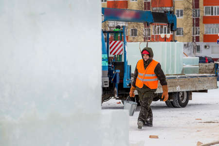 Portrait of a worker walking along the construction site of an ice town with a bucket in his handの写真素材