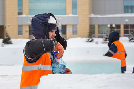 Portrait of a worker in profile in an orange vest opening a water bottleの写真素材