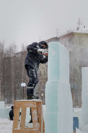 The sculptor cuts an ice figure out of ice by a chainsaw for Christmasの写真素材