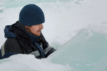 The sculptor cuts an ice figure out of ice with a chisel for Christmas