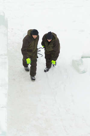 Two workers are pulling an ice block around the ice camp assembly site with forcepsの写真素材