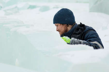 The sculptor cuts an ice figure out of ice with a chisel for Christmasの写真素材