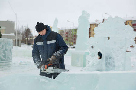 Worker with a chainsaw in hand at the assembly site of the ice townの写真素材