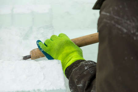 The sculptor cuts an ice figure out of an ice block with a chiselの写真素材