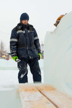 The sculptor cuts an ice figure out of an ice block with a chisel