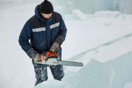 Worker with a chainsaw in hand at the assembly site of the ice townの写真素材