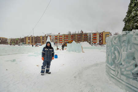 Portrait of a worker at an assembly site of an ice town in winter overalls
