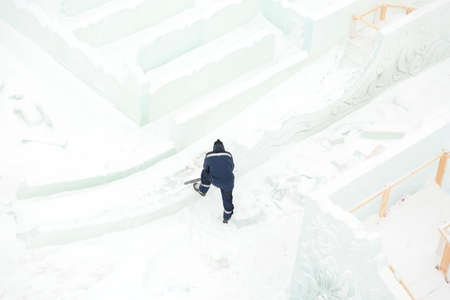 Worker with a chainsaw in hand at the ice figure