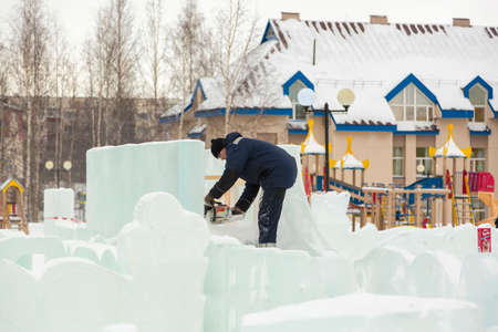 Worker with a chainsaw in hand at the ice figure