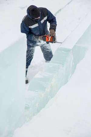 Worker with a chainsaw in hand at the ice figureの写真素材
