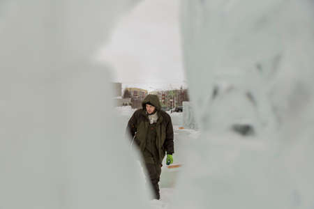 Portrait of a worker in a green jacket with a hood engaged in arranging an ice townの写真素材