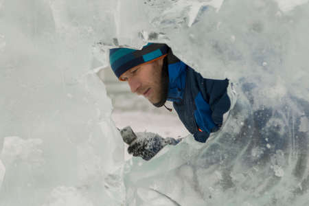 The sculptor cuts an ice figure out of ice with a chisel for Christmas
