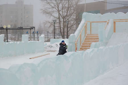 The sculptor cuts an ice figure out of an ice block with a chiselの写真素材