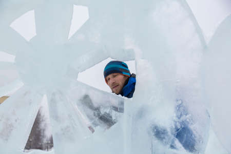 The sculptor cuts an ice figure out of ice with a chisel for Christmasの写真素材