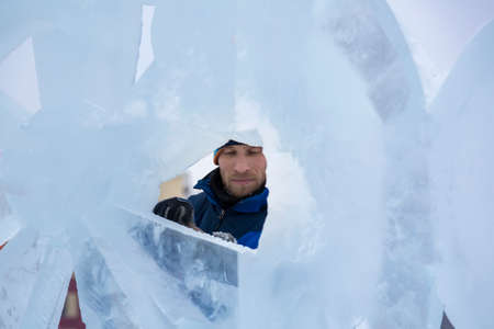 The sculptor cuts an ice figure out of ice with a chisel for Christmasの写真素材