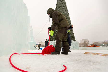 Electricians mount a power cable to illuminate ice figures.