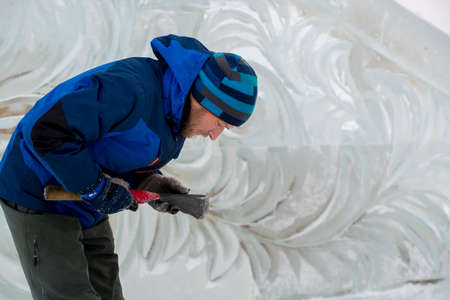 The sculptor cuts an ice figure out of a block of ice for Christmasの写真素材