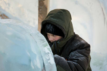 The sculptor cuts an ice figure out of ice with a chisel for Christmasの写真素材