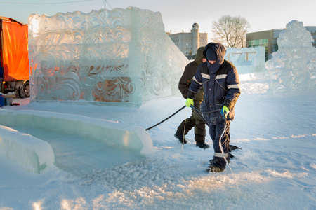 Installer at the construction site of the ice town hoses the rink to childrenの写真素材