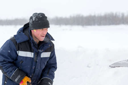 Worker in a blue jacket with a hood and a black knitted hat on his head