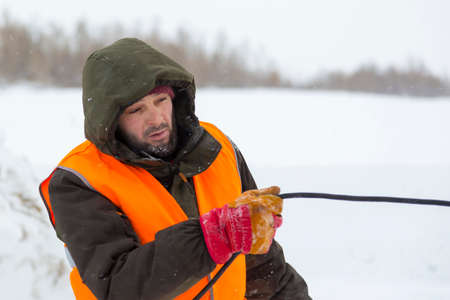 Worker in a green jacket with a hood and a reflective vest at the workplace