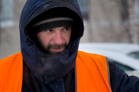 Worker in a blue jacket with a hood and a reflective vest at the workplace