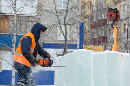 Workman installer in an orange reflective vest and helmet customize chainsaw ice plateの写真素材