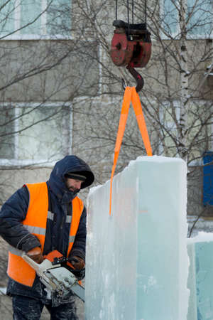 Workman installer in an orange reflective vest and helmet customize chainsaw ice plateの写真素材